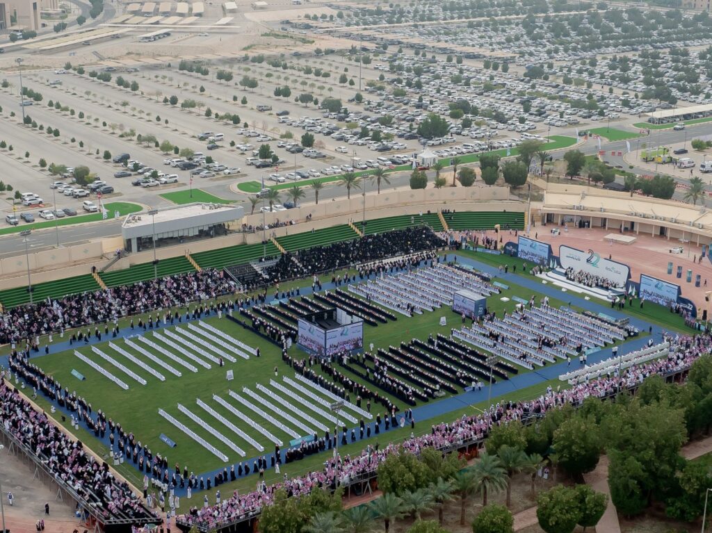 مشهد جوي لاستاد خارجي واسع في جامعة القصيم، وقد امتلأت صفوفه بالخريجين الذين تأخروا الغترة أو الشماغ السعودي مع العقال والبشت السعودي، وأدركوا أنهم قوى. يحيط بالاستاد مساحة خضراء منظمة مواقف سيارات واسعة وأشجار تحظى بتقدير روعة المكان.
