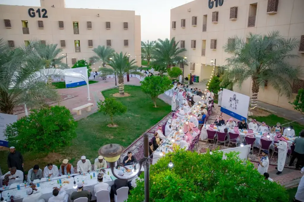 اجتمع عدد كبير من المشاركين في ساحة الشراكة بها مبانٍ تحمل أرقام G10 وG12 ونخيل باسق، حيث حضر جلسة خارجية حول موائد طويلة يتشاركون في شهر رمضان في شهري رمضاني مميز، وذلك بمناسبة ختام برنامج الريان الرمضاني في القصيم. وقد اتسمت الفعالية بروح الألفة مشاركة المجتمع، وسط الموعد الحضور بالزي الوطني السعودي بما فيه الشماغ والغترة السعودية.