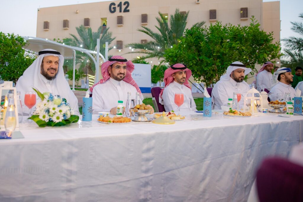 اجتمع عدد من الرجال مرتدين الغترة السعودية أو الشماغ والعقال والبشت السعودي حول مائدة خارجية طويلة تم إعدادها بأناقة وتزيينها بالزهور فقط والأطعمة، وذلك في مؤثرات طبيعية خضراء وخلفهم يظهر مبنى جامعة القصيم الحديث المعرف برمز G12.