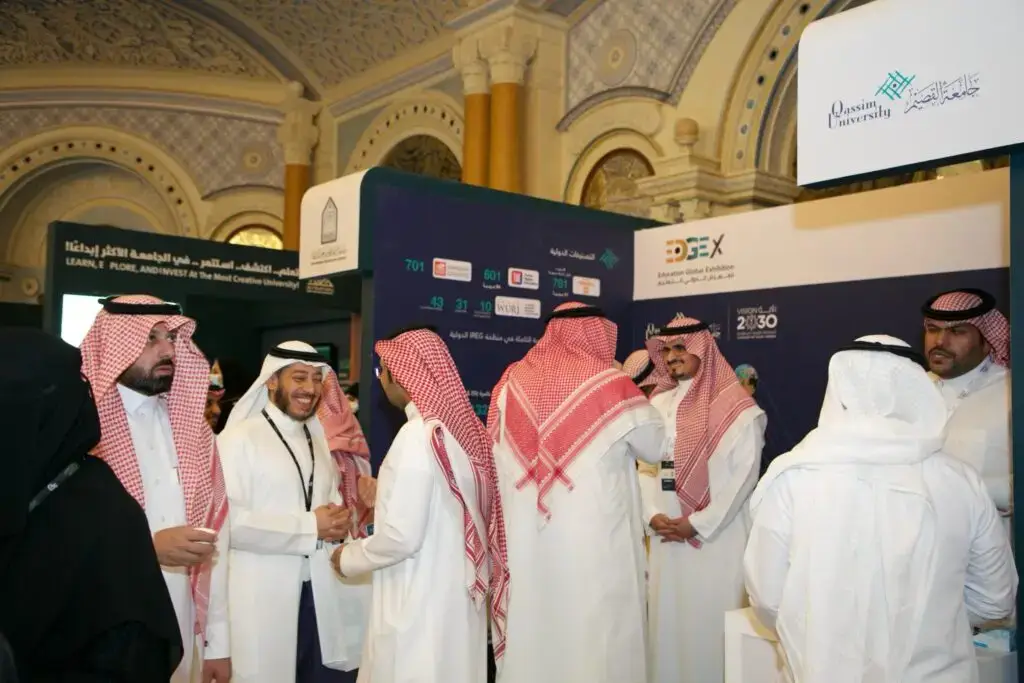 مجموعة من الرجال الحاضرين الغترة السعودية أو الشماغ والعقال، وبعضهم مرتدياً البشت السعودي، يتبادلون الحديث في جناح المعرض الدولي للمقام بمدينة الرياض. يحتوي على لافتة تحتوي على اسم الجامعة وأقواس تزيينية المكان فخمة. يبدو على بعض الحضور الابتسامة وهم بسيطين بطاقات التعريف الخاصة بهم، في مقطع فردي الاحترافية والرسمية التي تشارك مشاركة جامعة القصيم في الفعاليات الوطنية المشاركة.