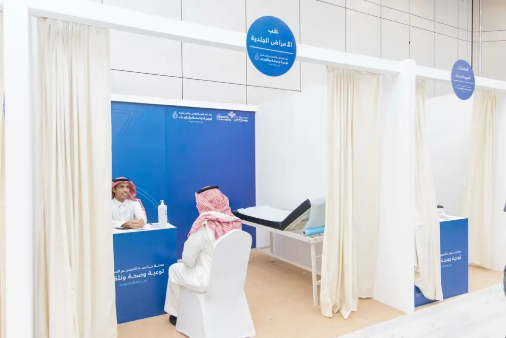 كولكشن منطقة الاستشارات الطبية في جامعة القصيم وحدات بيضاء ولافتات باللون الأزرق، حيث يتواجد طبيب يرتدي المعطف الطبي الأبيض ويتحاور مع أحد المراجعين الذين يرتدون البشت السعودي والعقال والغترة. اختارت منطقة الأسرة للفحص والستائر الخاصة، وذلك بفضل جهود التوعية والتثقيف الثقافي لكل الزوار.