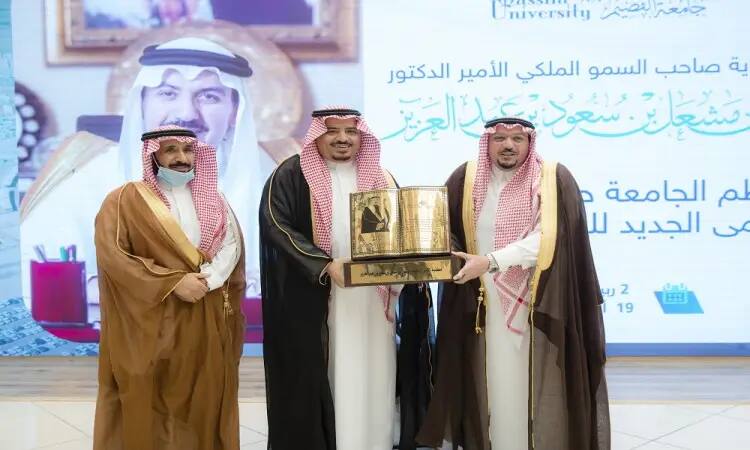 Three men wear the Saudi Arabian tunic or shemagh with an aqal, and one wears the official Saudi bisht. At Qassim University, the man in the center of the shield group hands a golden statue to the man standing on his right. It has Arabic text and a portrait of His Royal Highness Prince Dr. Faisal bin Meshal.