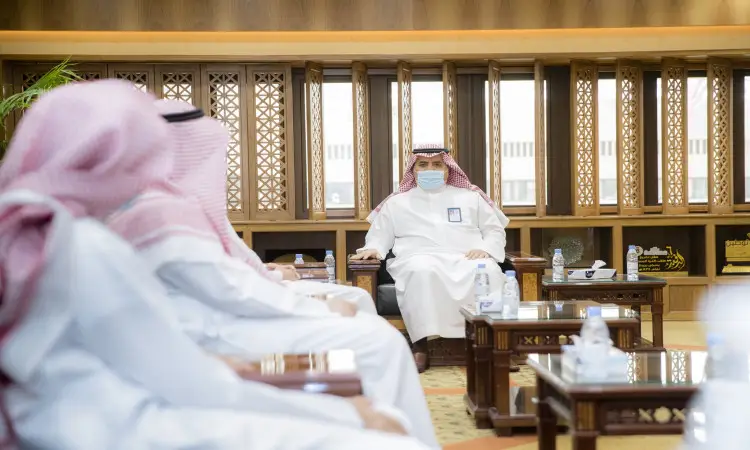 يجتمع مجموعة من الرجال مرتدين الغترة أو الشماغ السعودي مع العقال، تحديد الاتفاق مرتاً البشت السعودي، وذلك في قاعة بزيارة سيما في القصيم. يتوسط رجل الغرفة الكاميرا في المنتصف ويواجه ويضع ووضعاً كمامة طبية. كما وعدت على الطاولات أمامهم زجاجة ماء مكافأة ولوحات تقديرية.