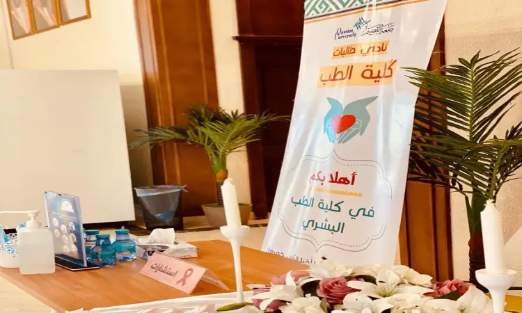 تزينت طاولة بأزهار جميلة، ووضعت عليها شموع وكتيبات تثقيفية ومياه، وقد توسطها شاب يرتدي شماغًا سعوديًا وقالًا وبشتًا يخرجان عن جواز السفر الوطني. متوسط، ورد بانر عصر "كلية الطب". يبرز هذا المشهد الرسمي لأول مرة في توعية الضريح المقامة في جامعة القصيم.