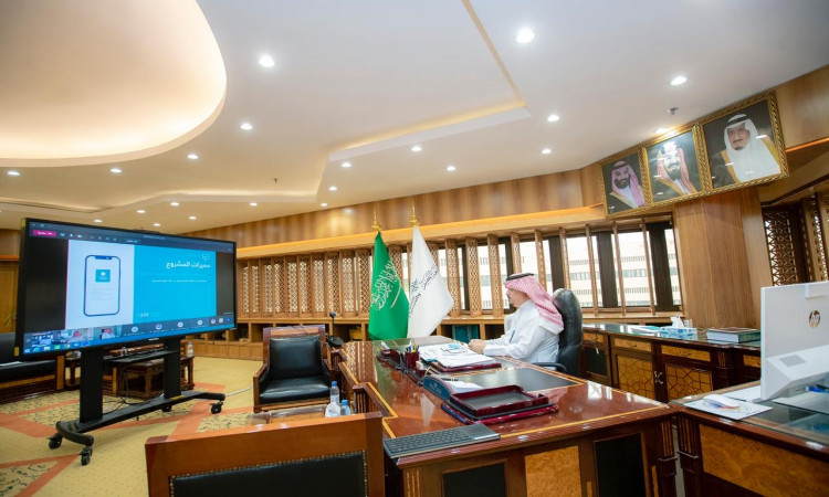 يجلس رجل ارتديا الغترة والعقال والبشت السعودي خلف مكتب فخم في أحد الطلاب الرسميين، وهو يشارك في محادثات تفاعلية افتراضية تريد عرض على شاشة أمامه. أخذ في الاعتبار أعلام المملكة العربية السعودية وحصر الوطن، بما في ذلك الطابعة الرسمية للمكان وانتماءه لجامعة القصيم.