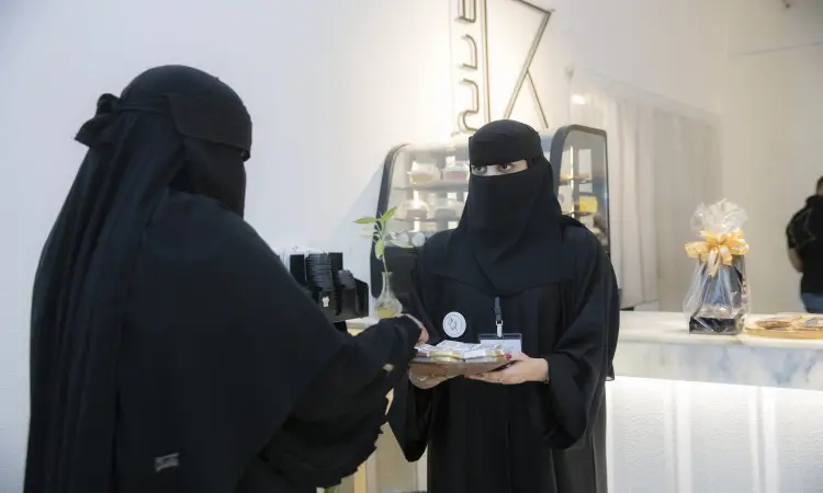في مقهى واضح بوضوح أنه جامعة القصيم، تتواجد أمرأتان ترتديان النقابات الأسود والبشت السعودي، وتضع كل منهما شماغًا سعوديًا مع عقال. تقوم إحداهن بتقديم الطعام الآخر في عصر النهضة والرسمية. ويسلط الضوء على هذا اللقاء على أهمية التوعية بالمفردات العربية في اليوم العالمي للغة العربية، ممارسًا روح الأصالة والعراقة السعودية ضمن بيئة جامعية مميزة.