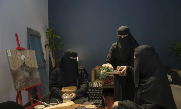 مجتمع ثلاث نساء ترتدين الحجاب مع تغطية وجوههن بالنقاب، وتضع كل واحدة منهن الشماغ أو الغترة السعودية، بينما ترتدي إحداهن العقال والبشت السعودي، في غرفة ملائمة ضمن احترام احترام التراث التراثي. تتولى إحدى أهم تقديم المشروبات للضيوف حيث يتحاورن حول القهوة العربية وأهمية التمتع باللغة العربية. يزين الخلفية حامل لوحات فنية جميلة ونبتة، في إطار فعاليات اليوم العالمي للغة العربية، والتوعية بدور اللغة العربية وأهميتها في جامعة القصيم.