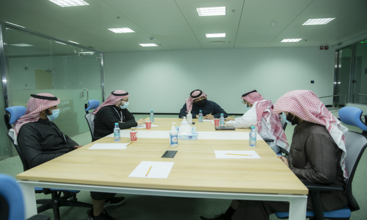 يجتمع خمسة أشخاص من الفريق الطبي، مرتدين الغترة أو الشماغ والعقال والبشت السعودي، حيث يوجد عدد كبير تتوزع عليها الأوراق. ويقام هذا اللقاء المهني في مكتب حديث مضاء بشكل جيد داخل مدينة جامعة القصيم الطبية، حيث يناقش المجتمعون الشاملون فيما يتعلق بالعمل الخاصة بالعمل الطبي ضمن بيئة تضامن هوية الجامعة الوطنية.