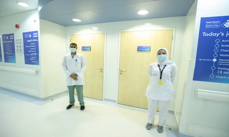 اتصل بزوجين منسوبي السائل الصحي بزيهم الأبيض الرسمي، ويرتدي كل منهما غترة سعودية وقال، ويعلقان على صدورهم البطاقة التعريفية. يظهران في ردهة نظيفة بمستشفى جامعة القصيم، بالقرب من أبواب خشبية مغلقة ولافتات إرشادية زري انتظروا ربما إلى مركز تطعيم فيروس كورونا.