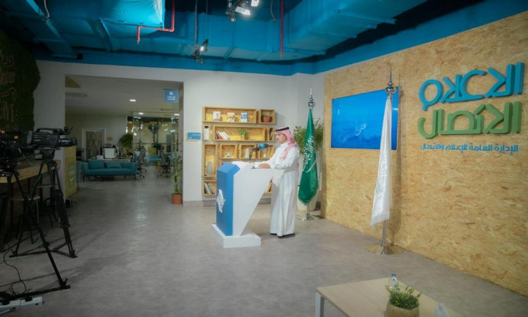 رجل سعودي يرتدي الزي الرسمي المكوّن من الغترة أو الشماغ والعقال، ومعطف البشت السعودي، القط الصغير أمام منصةية داخل الاستوديو حديث محاسب بكاميرات التسجيل. تعلم القراءة والكتابة باللغة العربية وعلم المملكة العربية السعودية وفوف الكتب، مع تفاعل إلى فعاليات يوم المعلم وملتقى الجامعة.