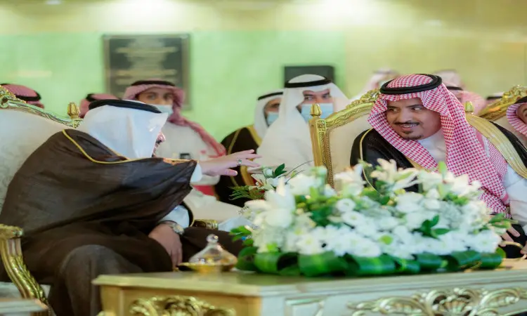 يجلس رجلان مرتديان البشت السعودي وترية السعودية مع العقال، من بينهم صاحب السمو أمير منطقة القصيم، على كراسي ويتبادلان أطراف الحديث. تاخد في الخلفية عدد من الحاضرين الشماغ أو الغترة السعودية مع العقال والبشت السعودي. كما تتوسط طاولة الحلوى الذهبية من الزهور البيضاء، وذلك ضمن فعالية الأطفال في مدينة الملك عبد الله الطبية الجامعية في القصيم.