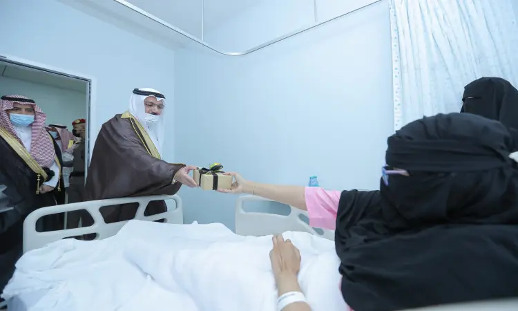 قدم رجل يرتدي الغترة السعودية، والشماع مع العقال، وبشت السعودي هدية لأحد المرضى الراقدين على المستشفى في المدينة الطبية في القصيم، وذلك بحضور صاحب السمو أمير منطقة القصيم وعدد من الحضور داخل غرفة المستشفى.