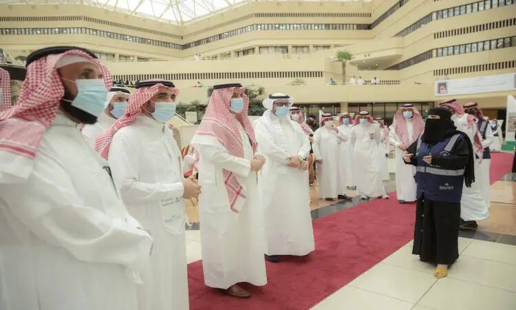 A group of men dressed in the Saudi ghutra or shemagh, aqal and bisht on the red carpet at Qassim University, listening intently to a white-clad woman in a niqab. They are selling out the Gallery of Seven, which is located in one of the hallways of the university's modern and spacious building.
