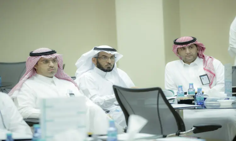 يجلس ثلاثة رجال يجلسون الغترة أو الشماغ السعودي والعقال والبشتاء السعودي حول طاولة بما في ذلك، وأمامهم زجاجة ماء ويترك ولوازم مكتبية، وهمتون باهتمام أثناء الاجتماع الرسمي. ويأتي ذلك في إطار جهود جامعة القصيم للتنمية الاجتماعية وشراكاتها العميقة مع شركاء التنمية.