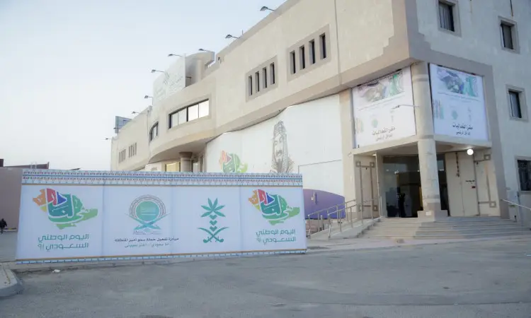 مبنى جامعة القصيم الحديث بلونه الأبيض، يكتسي حُلّة خاصّة تليق بمكانته الأكاديمية. تتزين صفحة بلافتات باللغة العربية، من جملة "أنا سعودي أعتز بهويتي" وشعارات اليوم الوطني. يؤدي ممراً مخصصاً إلى المدخل الرئيسي حيث يبرز أمامه لوحة جديدة جديدة "سمو أمير المنطقة". وتمثل مظاهر الاحتفاء الرسمي بالحضور شماغ سعودي وبشت وقال في صور الحضور والافتات النظيفة، أثناء ظهور الساحة ومضيئها بما في ذلك يعكس الرقي.