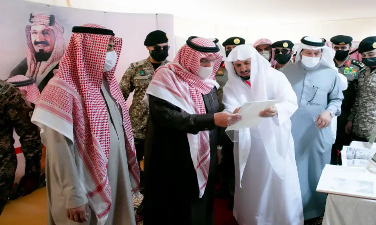 اتصل مجموعة من الرجال داخل جناح الجامعة، مرتدين الغترة أو الشماغ والعقال والبشت السعودي، إلى جانب أعضاء بزي عسكري. يقوم بتوقيع وثيقة الحضور، بينما يحضر في الخلفية صور كبيرة لقادة المملكة العربية السعودية وذكر سمو أمير منطقة القصيم.