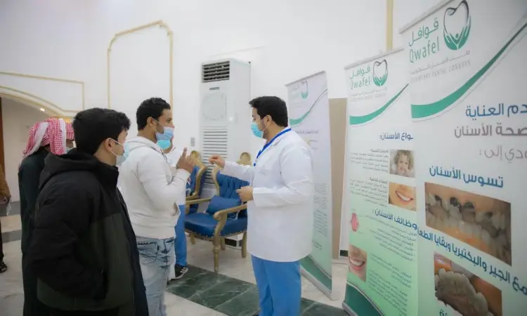 أبداً طبيب أسنان مرتدياً المعطف الأبيض والكمامة مع ثلاثة رجال لفت الغترة أو الشماغ والعقال والبشت السعودي، وذلك بفضل لوحات تعريفية بصراحة بصراحة الفم والأسنان، ضمن فعالية أُقيمت في مركز قوى قوافل طب الأسنان التابعة لجامعة القصيم. خلال الحوار، يقوم أحد بالحضور بالإشارة بيده أثناء قيام الباقون باهتمام؛ وتستعرض لاصقة لاصقة نصائح بالعربية لفرشاة أسنان الزجاجة الشفافة.
