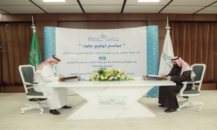 يرتدي الرجلان الغترة أو الشماغ والعقال والبشت السعودي يجلسان على طاولة بيضاء، ويتوقعان وثائق تتعلق بالتشغيل. وخلفهما لوحة كبيرة باللون الأزرق تتضمن نصوصًا عربية، بما في ذلك علامة المملكة العربية السعودية وأعلام جامعة القصيم، وذلك حتى الوصول إلى مكتب رسمي راقٍ.