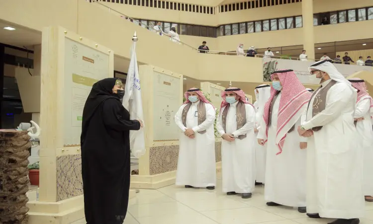 اللجنة النسائية ترتدي ملابس بيضاء مع مجموعة من الرجال الثوب الأبيض والشماج السعودي الأحمر والعقال، وقد خلفية هح النقابة بالشت السعودي، وذلك في معرض يوم وتقيم في القصيم، حيث تحجز في لوحات تعريفية تستعرض تاريخ الدولة السعودية.
