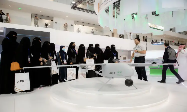 A Florida group of women in robes gather around a display of an unmanned aerial vehicle (UAV), while a demonstrator wearing a Saudi shemagh, qa'il and bisht explains the characteristics of the aircraft during the Global Defense Exhibition in Riyadh, in the presence of a number of Qassim University students who follow this modern exhibition with great interest.