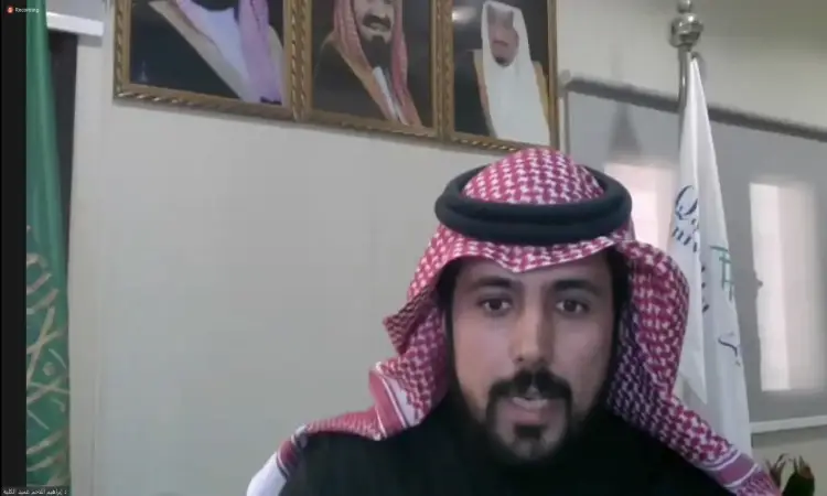 ضابط يرتدي الشماغ السعودي الأبيض والأحمر مع العقال التقليدي ومرتدياً البشت السعودي الأنيق والثوب الأسود، في مكتبه الرسمي في القصيم. يتم تحديد ما يمكن تحديده لتحديد كيفية تطوير مهارات اللغة العربية، والمحافظة على خلفه أعلام المملكة العربية السعودية وصور غير كافية على الحائط، مما يضفي مسؤولية رسمية ومهيباً على الاجتماع.