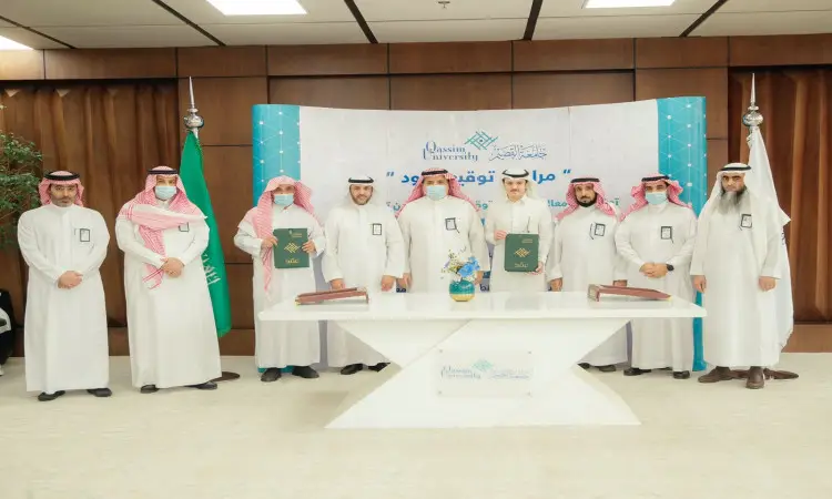 للاتصال عدد من الرجال مرتدين الزي السعودي الرسمي، الامتداد في الغترة أو الشماغ مع العقال، وبعضهم يضع البشت السعودي، قاعة مغلقة أمام طاولة رسم فوقها ملابس الأطفال. وتلاحظ خلفهم لوحة تحمل نصًا باللغة العربية فيما يتعلق بالتشغيل والصيانة في الجامعة التابعة لجامعة القصيم، بالإضافة إلى جزء اللوحة يبرز العلم السعودي.