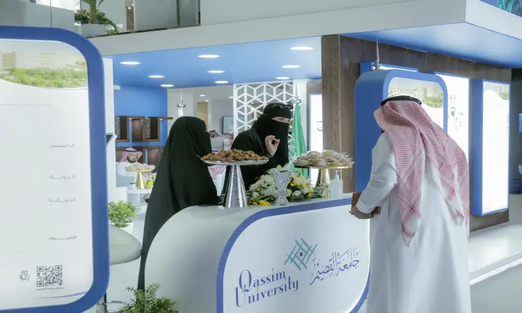 المؤتمر والمعرض الدولي للتعليم في مدينة الرياض، رجل الاتصال مرتدياً الشماغ السعودي والعقال والبشت الرسمي مخاطباً سيدتين يرتديان العباية والنقاب، وذلك في جناح جامعة القصيمدان بأصناف من الحلويات واللافتات الرسمية باللغتين العربية والإنجليزية ذات اللون الأزرق والأبيض.