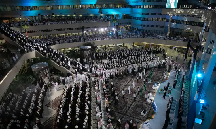 اجتمع جمع كبير من رجال مرتدين الغترة السعودية أو الشماغ مع العقال، وتعلوهم البشوت السعودية التقليدية، داخل بهو واسع يضاء بأضواء زرقاء في جامعة القصيم، وذلك للاحتفاء بتخريج طلاب الدفعة التاسعة عشرة. يتواجد البعض في مكان مخصص لهم، بينما يتواجدون في صفوف الفرق المخصصة لهم خصيصا لهذا الغرض.