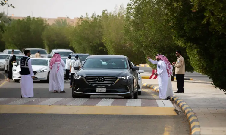 يشرف مجموعة من الرجال مرتدين الغترة السعودية، الشماغ، العقال والبشتاء السعودي على حركة السيارات – ومن ثم فإن المركبات مازدا تنظيم من نوع أسود SUV – في شارع تصطف على جانبيه بالقرب من الجامعة من خلال مؤتمرات حزب التحرير. ويتواجد عدد من المركبات المنتظرة في طابور الدخول، إلى جانب طالبات مرور الدفعة 19 بين أروقة المشاة القريبة.