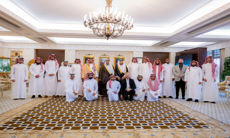 مجموعة من الرجال الحاضرين الغترة أو الشماغ والعقال، بالإضافة إلى البشت السعودي، مع الضيوف بلباس رسمي (بدلات السيدات)، من بينهم طلاب الجامعة، وأخيراً صورة جماعية في القاعة ذات طابع مميز تتميز بثريا فخمة وسجاد مزخرف وصور شخصية معلقة على الحائط خلفهم.