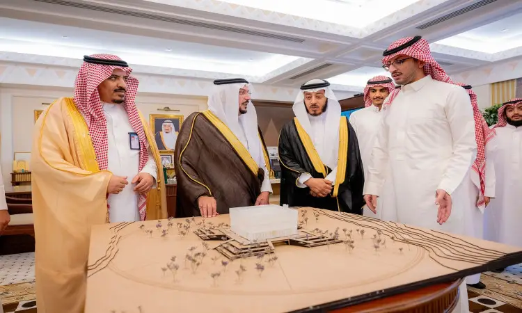 الاتصال مجموعة من الرجال مرتدين الغترة والشماع والعقال والبشت السعودي، جامعة طلاب الجامعة، حول مجسم معماري كبير يناقشون مشاريع المشاريع في قاعة فخمة تزيّنها صور مؤطرة و لهندسة راقية.