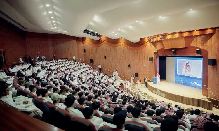يشهد جمع غفير من الحضور بلباسهم التقليدي في الثوب والبشت السعودي، بالإضافة إلى تكملة الغترة السعودية أو الشماغ والعقال، مؤتمر "برنامج طموح" في الجلسة الحديثة. ويستمع الحضور باهتمام لكلمة معالي رئيس جامعة القصيم الذي تلمس على المنصة، بينما تعرض على الشاشة الكبيرة خلفه مداخلة لمتحدث آخر.