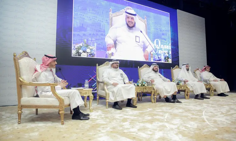 يجلس خمسة رجال مرتدين الغترة أو الشماغ السعودي مع فساتين العقال والبشت السعودي على كراسٍ فخمة فوق منصة الاحتفال، وتجمع جانبهم تنسيقات تنسيقات. تم تسجيل خلفهم شاشة كبيرة صورة لمعالي رئيس جامعة القصيم مبتسمًا، في سيتارين العاكس الرسمي للفعالية المتزامنة مع برنامج "طموح" المعلنة رسميًا.