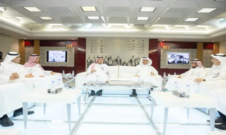 يجتمع ستة رجال ينتظرون البشتاء السعودي والغترة أو الشماغ والعقال في قاعة حديثة بمكتبة الملك فهد الوطنية، حيث ينخرطون في نقاش رسمي. توسطتهم طاولات وُضِعت عليها مياه، بينما كانت تجلس على الحائط الخلفي لشاشتان تم التقاطها وبيانات معقدة بالفهرس السعودي الموحد.