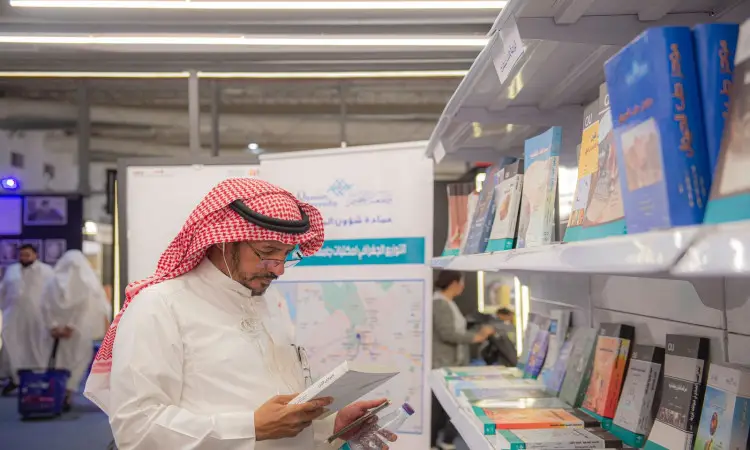 ارتدى رجل الثوب السعودي الرسمي مع غترة وعقال، بالإضافة إلى بشت سعودي، إنتاج كتاباً في معرض الرياض الدولي للكتاب، وأقفاً بجوار رفوف تنفيسة بالكتب. يتضمن قطع الخلفية من الزائرين إلى جانب العرض نصوصًا باللغة العربية.