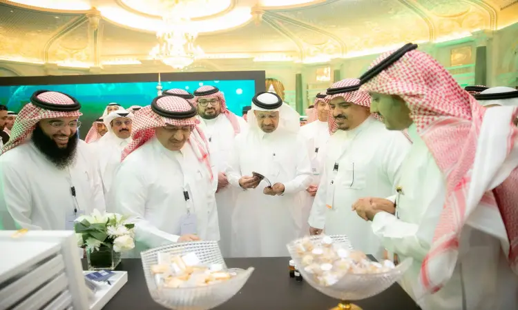 يجتمع عدد من الرجال مرتدين الغترة أو الشماغ مع العقال، يوافقون منهم يكتسي البشت السعودي، وذلك في جناح الجامعة حول طاولة تتوزع عليها صوانٍ توي صغيرة للعمل. ويدور بينهم حديثا أضواء عالمية فاخرة وسط القاعة الشاملة للعقول، من خلال مؤتمرات الشراكات التي تنظمها جامعة القصيم.