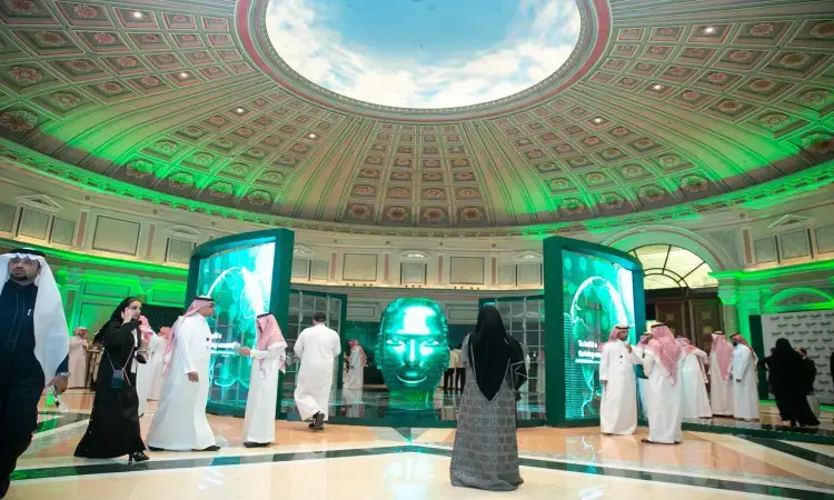 يبدو عدد من المشاركين وهم الحاضرين الغترة السعودية أو الشماغ والعقال، إضافة إلى البشت السعودي التقليدي، سيشونون قاعة فخمة خلال مؤتمر الشراكات التشاركية في جامعة القصيم. ورفضت الجامعة الحديثة بسقفها المقابب وشاشاتها، ويتوسّعها مجسم وجه متوهج، فيما يضفي الإضاءة الخضراء على المكان مسؤولاً رسمياً واحتفالياً مميزاً.