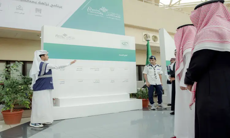يقوم شاب يرتدي صديرية بالإشارة إلى لوحة عرض سوداء أمام مجموعة من الرجال الذين يرتدون الزي السعودي الرسمي التاسع في الغترة أو الشماغ والعقال والبشت السعودي، ويستعرض جهود المملكة في مكافحة غيره. كما ينقص منها بعض النباتات المزروعة وأحد الناس يرتدون زي الكشافة.