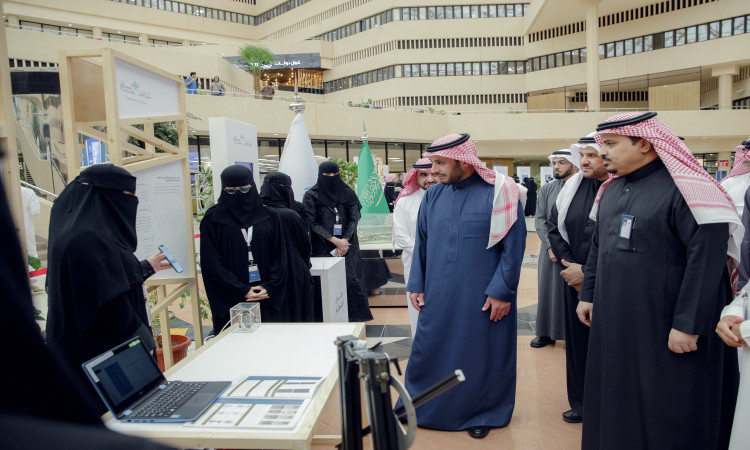 الاتصال مجموعة من الرجال تولى الغترة السعودية مع العقال والبشت السعودي، إلى جانب النساء بزي رسمي، وهم يتابعون باهتمام إحدى الأمهات أثناء تقديمها عرضاً تعريفياً في جناح "معمل كود الجامعة" ضمن الفعالية، حيث أبرزت أعلام المملكة العربية السعودية والعروض التعريفية التي تتمحور حول ريادة الأعمال الرقمية في الخلفية.