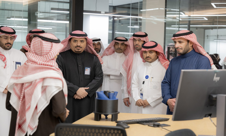 يجتمع مجموعة من الرجال مرتدين الغترة أو الشماغ والعقال بالإضافة إلى البشت السعودي في مكتب بمعمل كود الجامعة، حيث يجتمعون باهتمام شخص واحد ويتبادلون النقاشات حول ريادة الأعمال الرقمية من مكتب يحوي شاشة الكمبيوتر وبعض المستلزمات المكتبية.