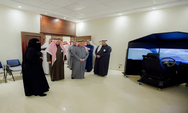 مجموعة من الأشخاص تسمم الغترة أو الشماغ السعودي والعقال والبشت السعودي داخل قاعة مضاءة بإشراق جامعة القصيم بجوار جهاز محاكاة القيادة، حيث يستمعون إلى معالي وزير التعليم أثناء شرحه. وتضفي الجدران ذات اللون السكري وأرضية المروحة المبلطة قراءة من الرونق على مرافق الجامعة.
