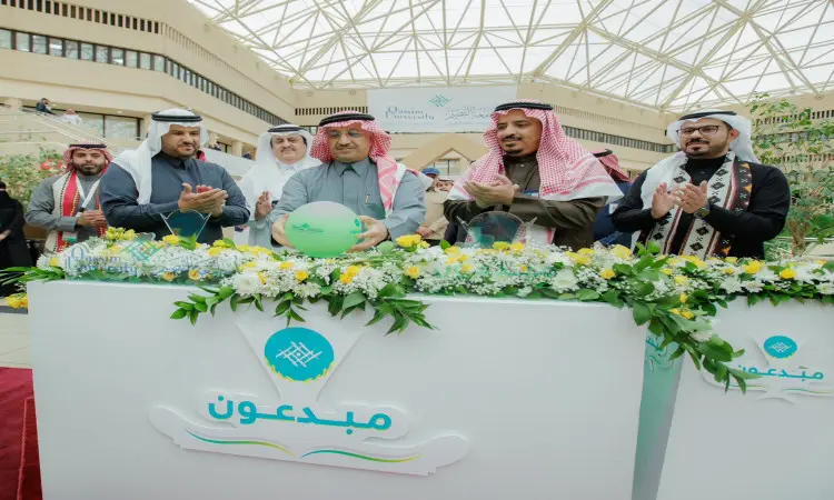مجموعة الاتصال من رجال الغترة أو الشماغ والعقال والبشت السعودي، يتقدمهم معالي وزير التعليم، خلف منصة الزينة بالزهور خلال رسمي في القصيم. تبدو على وجوههم علامات السرور وصف صفيقون ويبتسمون. أنشأ بناء نص عربي بارز بالإضافة إلى اللون الأخضر تحت قبة فخمة.
