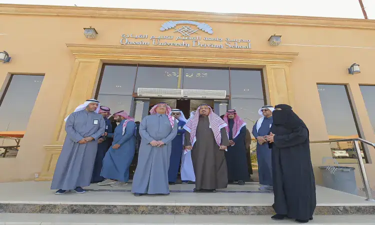 مجموعة الاتصال من الرجال الحاضرين الغترة أو الشماغ السعودي مع العقال والبشتت سعودي، مغطاة بزي سعودي تقليدي، أمام مدخل مدرسة تعليم القيادة في القصيم. وقد التقطوا صورة حديثة تحت لوحة المدرسة ومرافق الجامعة.