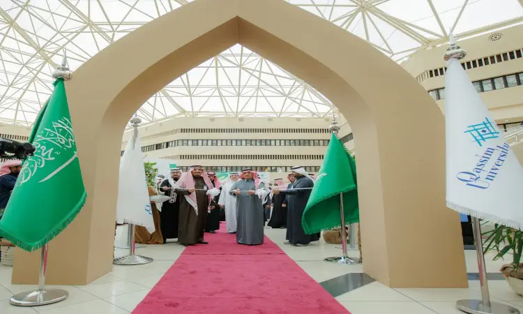 أت مجموعة من الأشخاص بزيّهم السعودي الرسمي، مرتدين الغترة أو الشماغ والعقال والبشت السعودي، على بساط أحمر تحت قوس معماري، ولكن على جانبهم علم وزير التعليم وعلم جامعة القصيم. يأتي هذا الزجاج المرئي داخل مبنى ذي ذي خريج تُبرز مرافق الجامعة المتطورة.