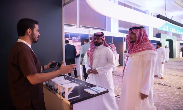 رجل يرتدي زياً بنياً وهو يتحاور مع رجلين يرتديان الغترة السعودية والعقال والبشت السعودي، وذلك من خلال المؤتمر والمعرض الدولي للمهندسين بالرياض، بالقرب من جناح كلية الهندسة الذي حرّر بحق تعريفية. ويمكن مشاهدة المشاركين والأجنحة المختلفة.