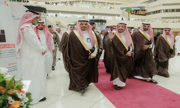 يسير مجموعة من الرجال السعوديين مرتدين الغترة أو الشماغ والعقال والبشت السعودي، يتقدمهم صاحب السمو أمير منطقة القصيم، على الحمراء داخل جامعة القصيم خلال ممارسات مهنة المهنة. وتتميز بالعلامات الابتسامة ويحيون الحضور، حيث تعاني من مجموعات من الأشخاص وتزين الأماكن باقات الزهور.