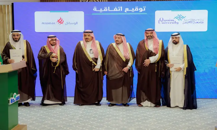 A number of men wearing the Saudi shemagh, aqal, and besht are contacted on a podium, and behind them a large blue screen on which the logos of Qassim Company and University are drawn. In the background is the signature of His Highness the Emir of Qassim Province.