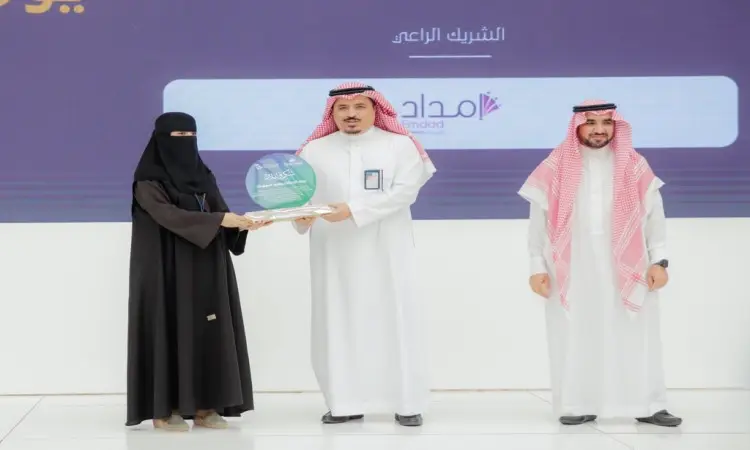 حصلت على جائزة بدلة بيضاء ونقابية من رجل يرتدي بشتًا سعوديًا فوق الزي الأبيض، مع شماغ سعودي وقالب، وذلك على الملابس الخشبية من خلال فعاليات يوم المهنة التقنية في جامعة القصيم. ووقف إلى جانبهما ممثل من وزارة الاتصالات، مرتديًا هو الآخر ثانيًا أبيض وبشت سعوديًا مع غترة سعودية وقال، مبتسمًا أثناء فترة الترميم.