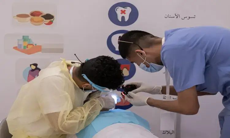 يقوم باثنين من المختصين في مجال الطبخ، مرتديان الكمامات والمستلزمات الضرورية بالإضافة إلى الغترة والعقال والبشت الرسمي السعودي، بفحص أحد المرضى باستخدام الضوء يدوياً داخل إحدى العيادات، وذلك ضمن فعاليات حملة صحة التي تهدف إلى التوعية الصحية. كما هو الحال في الملصقات الخلفية توعوية صادقة وصحة الفم والأسنان تحمل شعار جامعة القصيم.