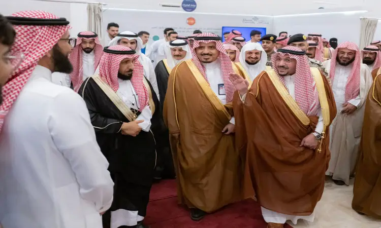 يجتمع مجموعة من الرجال السعوديين، مشاهير الثوب السعودي مع الشماغ أو الغترة السعودية والعقال، في فعالية مقامة داخل قاعة مركز قبة. ويتوسط الحضور عددٌ من المشاركين وهم يحتفلون بالبشت السعودي المزيّن بالكرة الذهبية، حيث يبادلون التحية والابتسامات بمناسبة احتفال حملة الجامعة الرابعة، وذلك بحضور صاحب السمو أمير منطقة القصيم.
